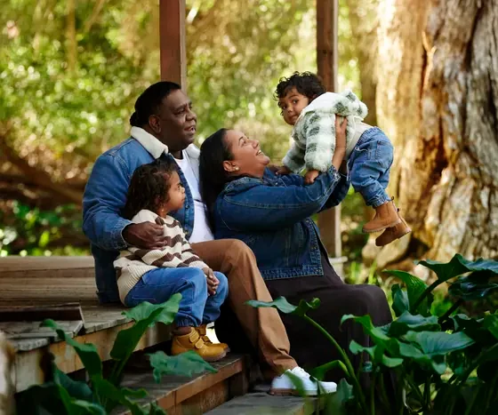 Parents in denim jackets with two little ones in cream stripes on the veranda at Premier Studio