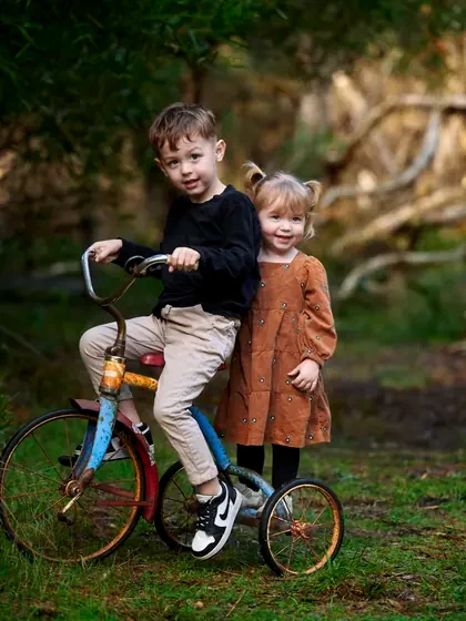 Brother in black and sister in a brown dress with a vintage bicycle in the bush at Premier Studio