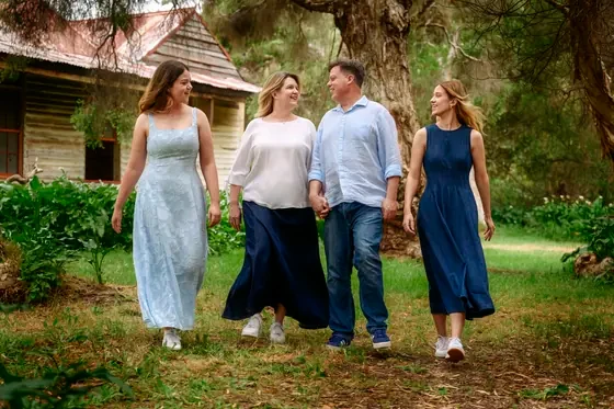 Family of four in light blue, navy and cream walking past the cottage at Premier Studio