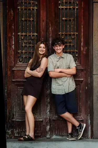 Teenage siblings in a black dress and sage shirt at the aged doors, Premier Studio