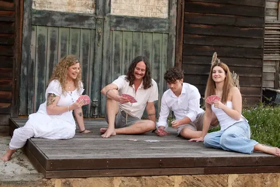 Family of four in white and washed denim relaxing on the timber deck at Premier Studio