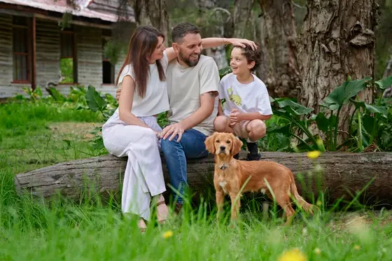 Parents in cream and denim with their son and puppy on a fallen log at Premier Studio