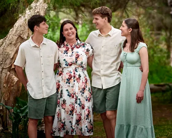 Family of four in sage green, cream and a soft floral dress among the trees at Premier Studio