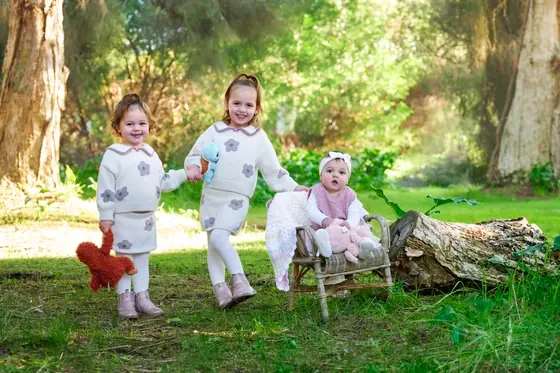 Three sisters in pink and cream outfits walking through the garden at Premier Studio