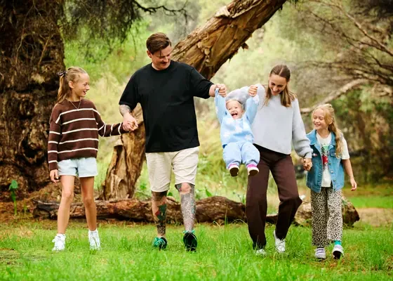 Family of six in chocolate brown, black, khaki and pale blue walking through the bush at Premier Studio