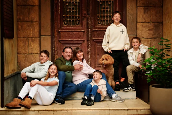 Family of six in cream, sage green and soft pink with their spoodle on the cottage steps at Premier Studio