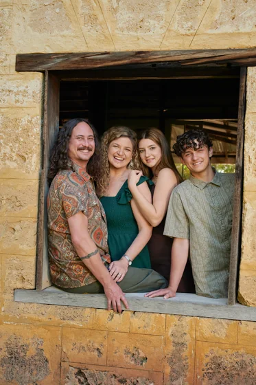 Family of four in emerald green, black and earthy florals framed by the limestone window at Premier Studio