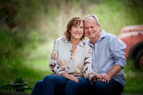 Couple in a cream floral blouse and chambray blue shirt seated in the bush at Premier Studio