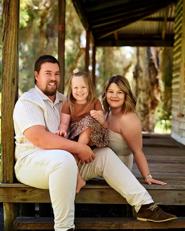 Parents in cream with their daughter in caramel and floral on the veranda steps at Premier Studio