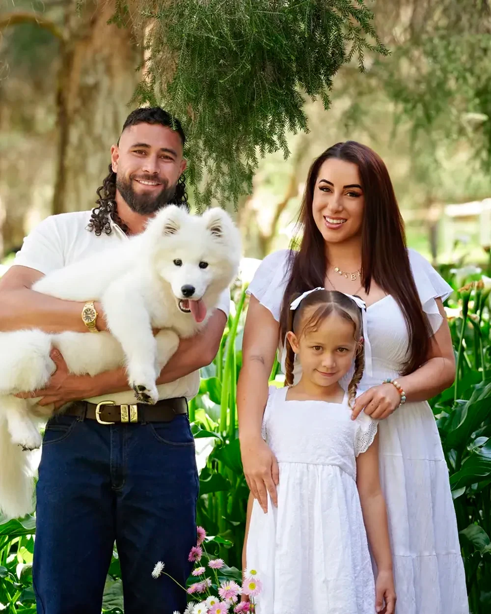 Family in white with dad in denim holding their Samoyed among the arum lilies at Premier Studio