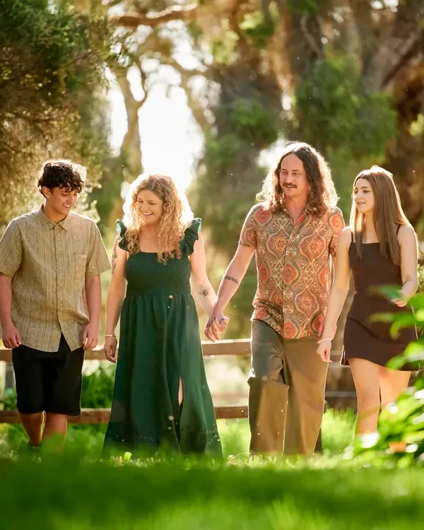 Family of four in emerald green, olive and black walking through the bush at Premier Studio
