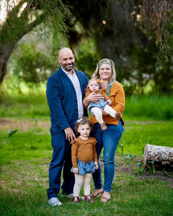 A large family photographed outdoors wearing bold colours