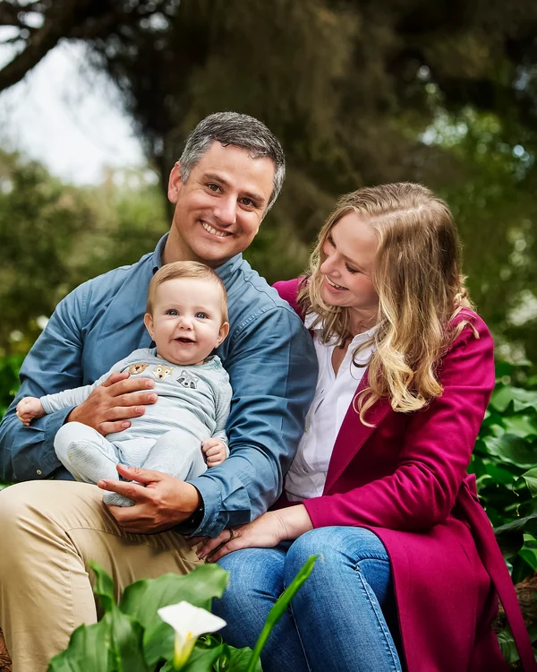 A large family photographed outdoors wearing blues, greens and tan