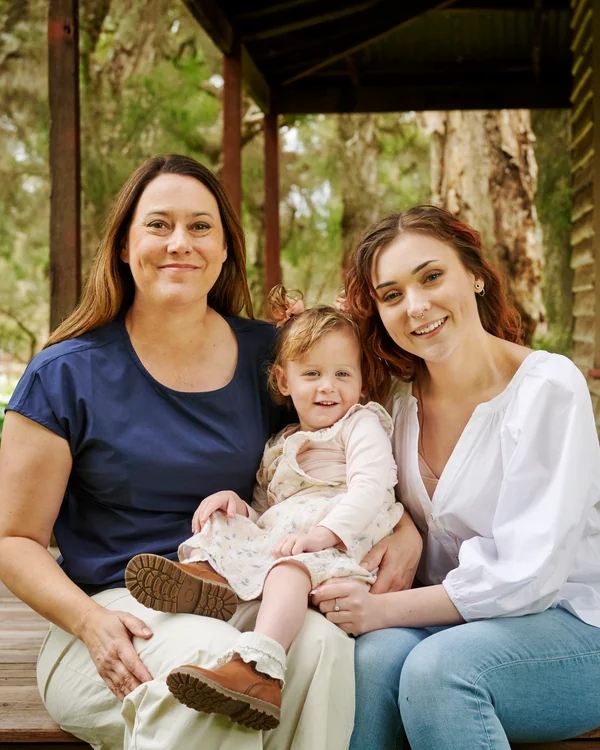 A large family photographed outdoors wearing bold colours