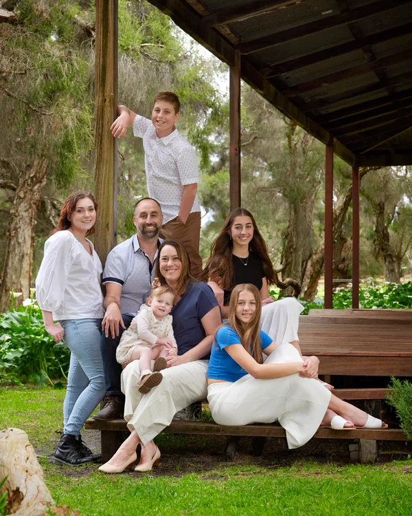 A large family photographed outdoors wearing white and denim