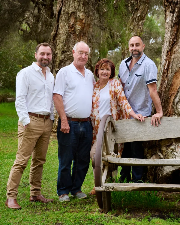 A large family photographed outdoors wearing blues, greens and tan