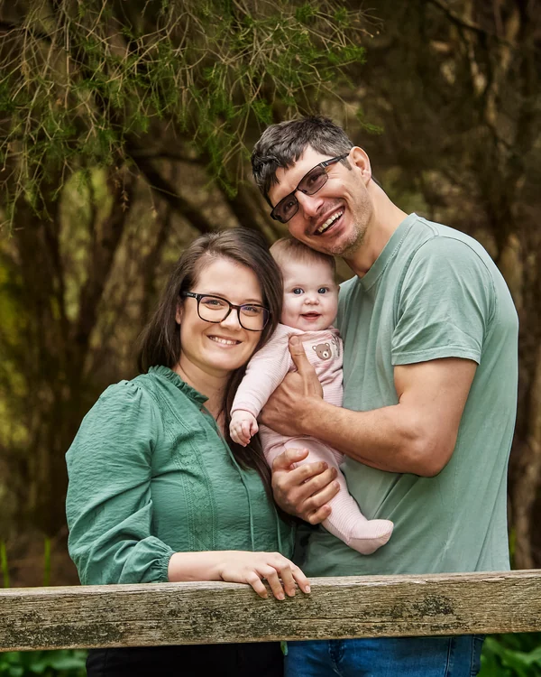 A large family photographed outdoors wearing blues, greens and tan