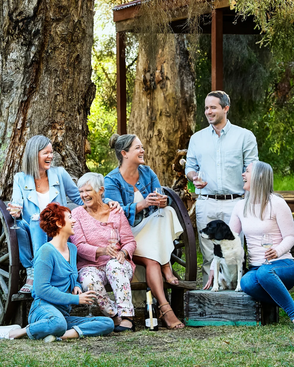 A large family photographed outdoors wearing blues, greens and tan