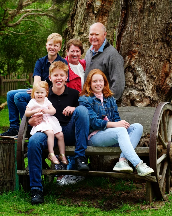 A large family photographed outdoors wearing bold colours