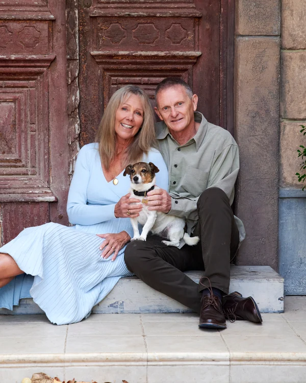 A large family photographed outdoors wearing blues, greens and tan
