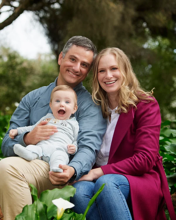 A large family photographed outdoors wearing blues, greens and tan